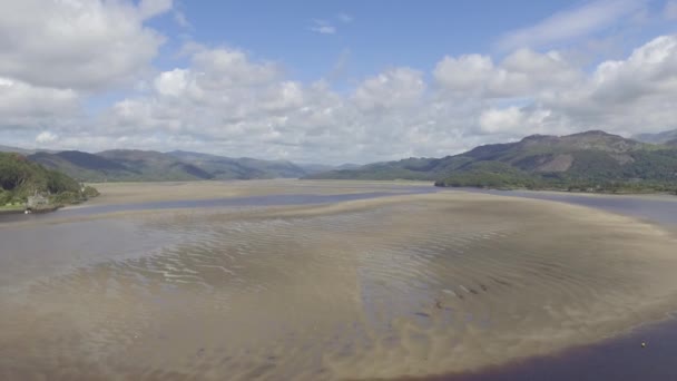 これは ビューでSnowdonia国立公園のウェールズの丘や山と川Mawddachの砂と水の上に飛んで移動空中ショットです — ストック動画