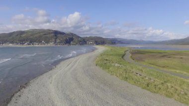 Fairbourne Stony plajının arka planda Barmouth ve köprüsünü gösteren sabit bir görüntüsü..