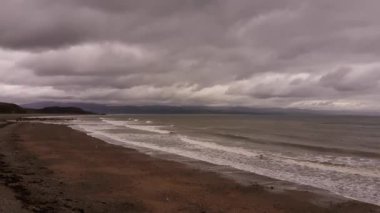 Criccieth sahili bulutlu ve sıkıcı bir günde kıyıya vuran dalgalarla dolu..