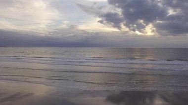 Deniz dalgaları bulutların arasından plaj güneşini süzüyorlar.