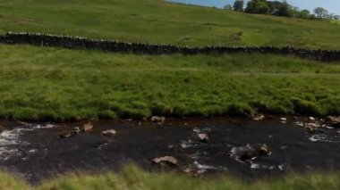 Dolly tarzı bir taşra duvarı ve deresinin (aslında bir drone ile çekilmiş) çekimi. Ateş, Carnforth 'daki Barbon Beck Vadisi' nde edilmiş. Sağdan sola gidiyor..