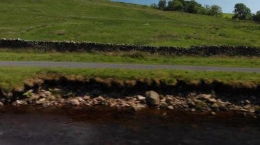 Dolly tarzı bir taşra duvarı ve deresinin (aslında bir drone ile çekilmiş) çekimi. Ateş, Carnforth 'daki Barbon Beck Vadisi' nde edilmiş. Soldan sağa gidiyor..