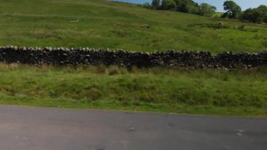 Birleşik Krallık 'ın Cumbria bölgesindeki bir taşra duvarının bir Dolly tarzı (aslında bir drone ile çekilmiş) çekimi. Tek yollu yol ve çim sınırının daha fazla görünmesi için çekim başlıyor..