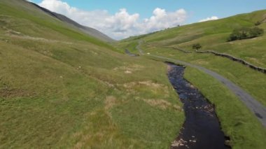 Barbon Beck Vadisi üzerinde uçuyor, Carnforth, Lancashire, İngiltere. Bu çarpıcı kırsal bölgede iki aracın çekim alanına girdiği küçük bir köy şeridi boyunca akan bir dere var..