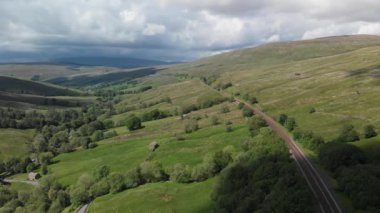 Dent demiryolunun ve Cumbrian kırsalının çevresini gösteren statik bir görüntü. Manzara yeşil ve güneşli Haziran 'da çekildi..