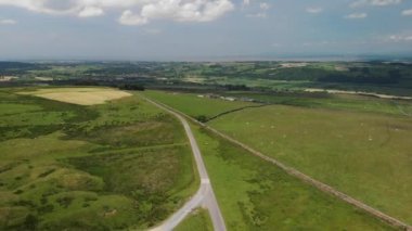 Caton Moor 'a doğru hızla yükselen ve Grange-over-Sands' e bakan bir görüntü. Lancaster. Güneşli ama bulutlu bir yaz gününde göz kamaştırıcı yeşil kırları görebilirsiniz..