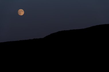 Büyük ay dağın üzerinden parlar. Gece