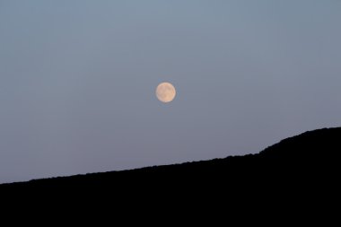 Büyük ay dağın üzerinden parlar. Gece