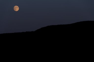 Büyük ay dağın üzerinden parlar. Gece