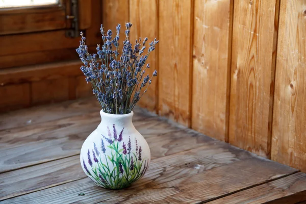 Penceresinde bir vazoda lavanta çiçekleri vardır