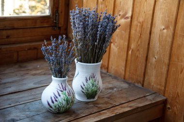 Penceresinde bir vazoda lavanta çiçekleri vardır