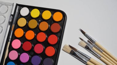 Beyaz arkaplanda suluboya ve boya fırçaları paleti