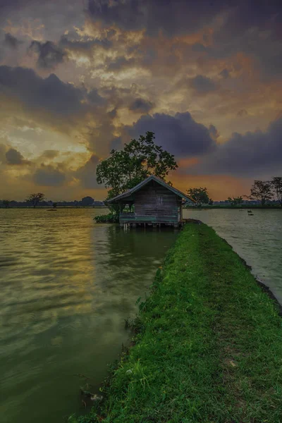 Cikoneng-Bandung şehrinde gün batımında kır evi ve göl manzarası. Seçici odaklanma, uzun pozlama.