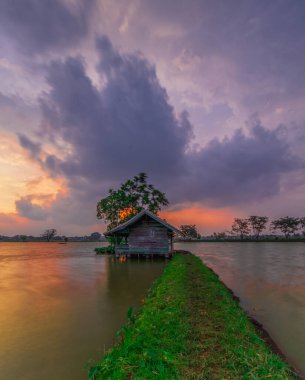 Cikoneng-Bandung şehrinde gün batımında kır evi ve göl manzarası. 