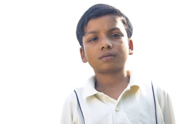 Kriket üniformalı bir çocuk ayakta duruyor.