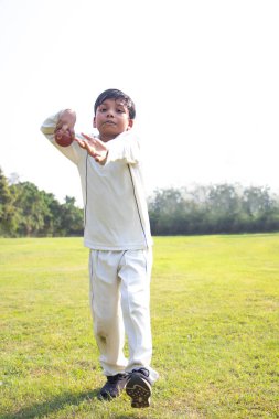 Genç bir çocuk krikette bovling bacağını çeviriyor.