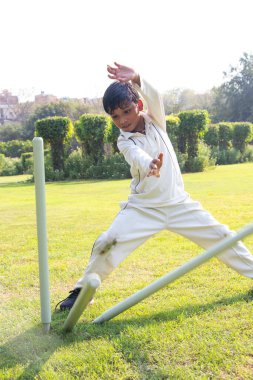 Kriket maçında sahada oynayan bir çocuk.