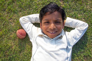 Üst açı, genç bir çocuk yerde yatıyor ve kameraya bakıyor.