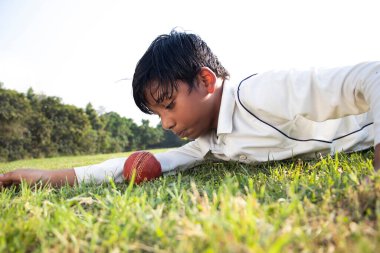 Kriket maçında sahada oynayan bir çocuk.