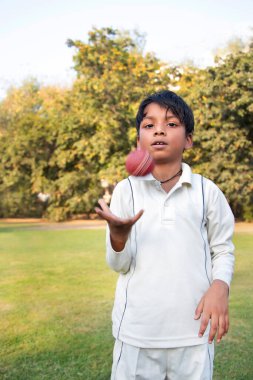 Kriket topu tutan genç bir çocuk.