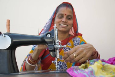 Dikiş makinesindeki kadın Hindistan 'ın kırsal bir köyünde kıyafet yapıyor.