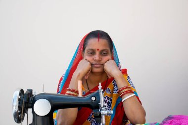 Hindistan kırsalında dikiş makinesiyle oturan Hintli kadın.