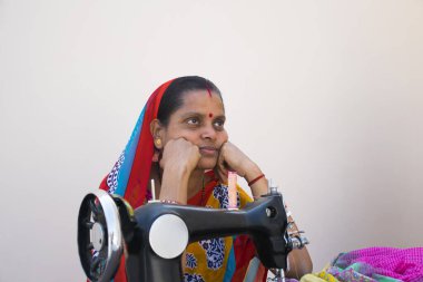 Hindistan kırsalında dikiş makinesiyle oturan Hintli kadın.