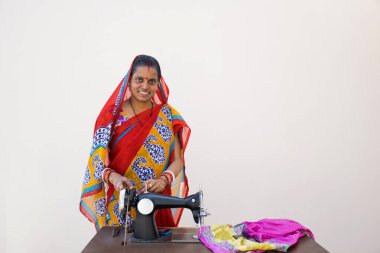 Hindistan kırsalında dikiş makinesiyle duran kendine güvenen bir kadın.