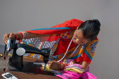 Hindistan 'ın kırsal kesimlerinde Hintli bir kadın kumaş dikiyor.