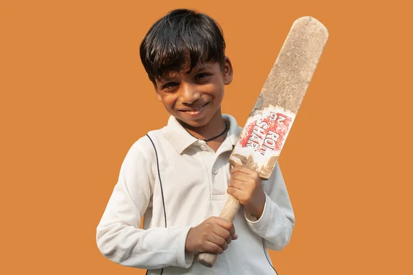 Kriket üniformalı ve elinde sopa tutan bir çocuk.