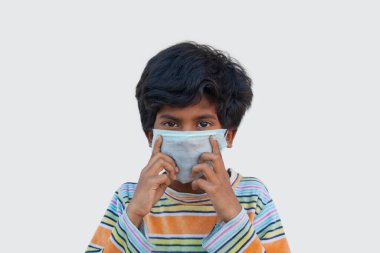 Çocuk koruyucu maske takıyor.