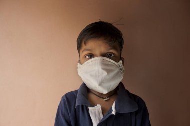 Coronavirus ve Hava kirliliği pm2.5 konsepti. Corona virüsünü durdurmak için maske takan Hintli çocuk.