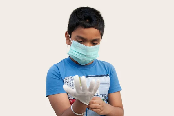 Koruyucu maske takan ve lastik eldiven giyen çocuk.
