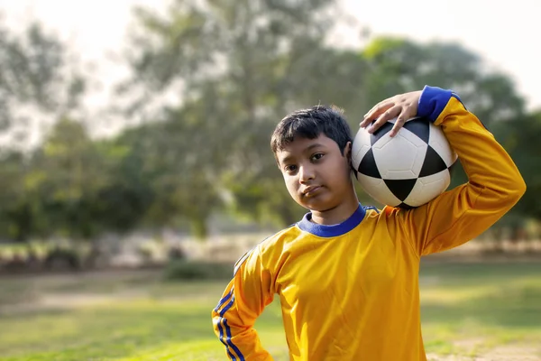 Omzunda futbol topu tutan bir gencin portresi.
