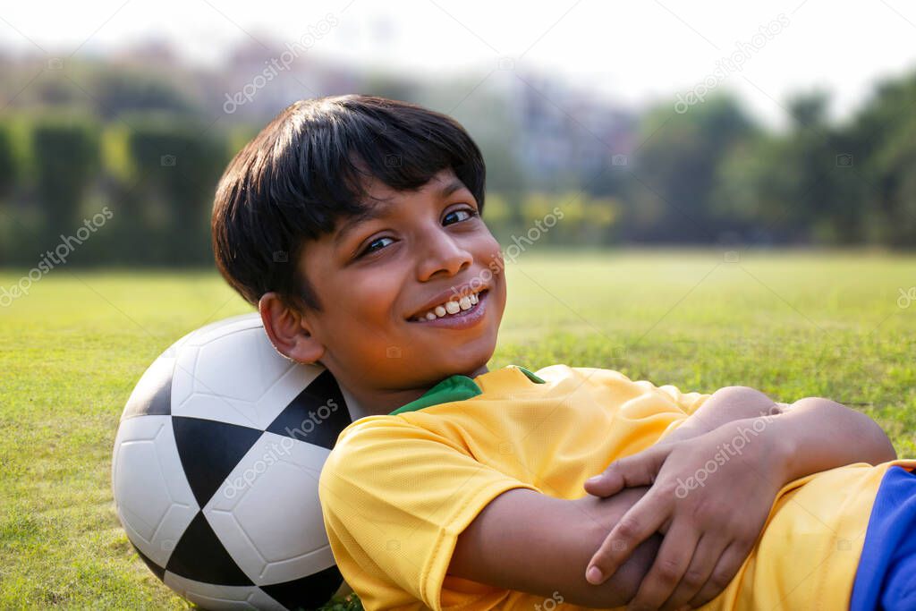 Young boy laying in the ground with football