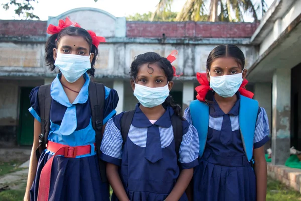 Three indian Rural School Girl wearing Mask Standing in school