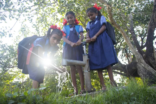 Indian Rural School Girls drinking water from Tubewell at village