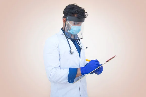 Laboratuvar önlüğü giyen bir sağlık çalışanı not defteri ve kalem yazıyor.