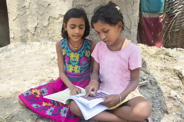 Evde kitap okuyan iki Hintli kırsal kız.