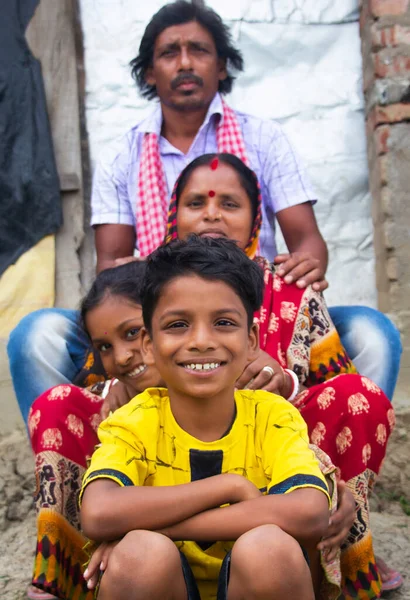 Indian Rural Parents and their two children sitting in front of the family house in village
