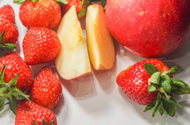 Beyaz arka planda bir sürü kırmızı olgun çilek yatıyor.