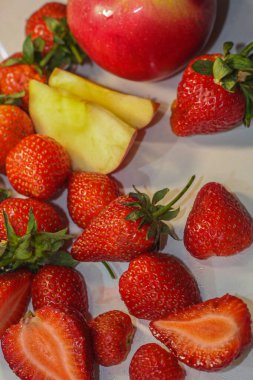 Beyaz arka planda bir sürü kırmızı olgun çilek yatıyor.