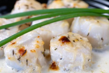 Mükemmel pişirilmiş deniz tarakları, yeşil soğanla servis ediliyor.