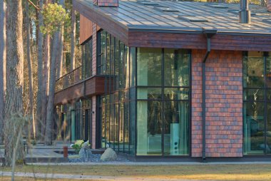 Ormanda büyük pencereleri olan büyük, güzel ve şık bir ev..