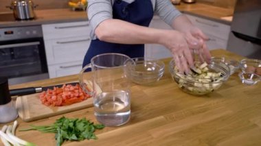 Kız pişirmeden önce patlıcanları tuzlu suya batırıyor.