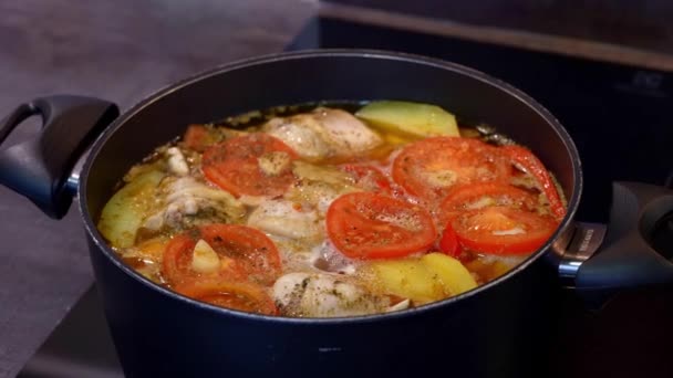 Verse jonge aardappelen in een pan met tomaten en kip erop — Stockvideo