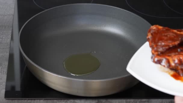 İnsan yemek pişirmek için beyaz tabaktan yağlı bir tavaya et taşır. — Stok video