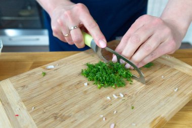 Tahtada yiyecek hazırlamak için dereotu kesme işlemi.