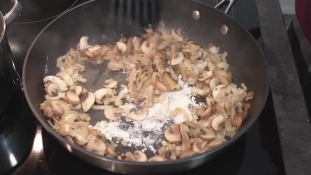 Bak de champignons met uien in bloem in een koekenpan — Stockvideo