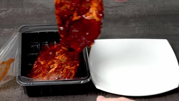 İnsan, plastikten yemek pişirmek için eti beyaz bir tabağa aktarır. — Stok video